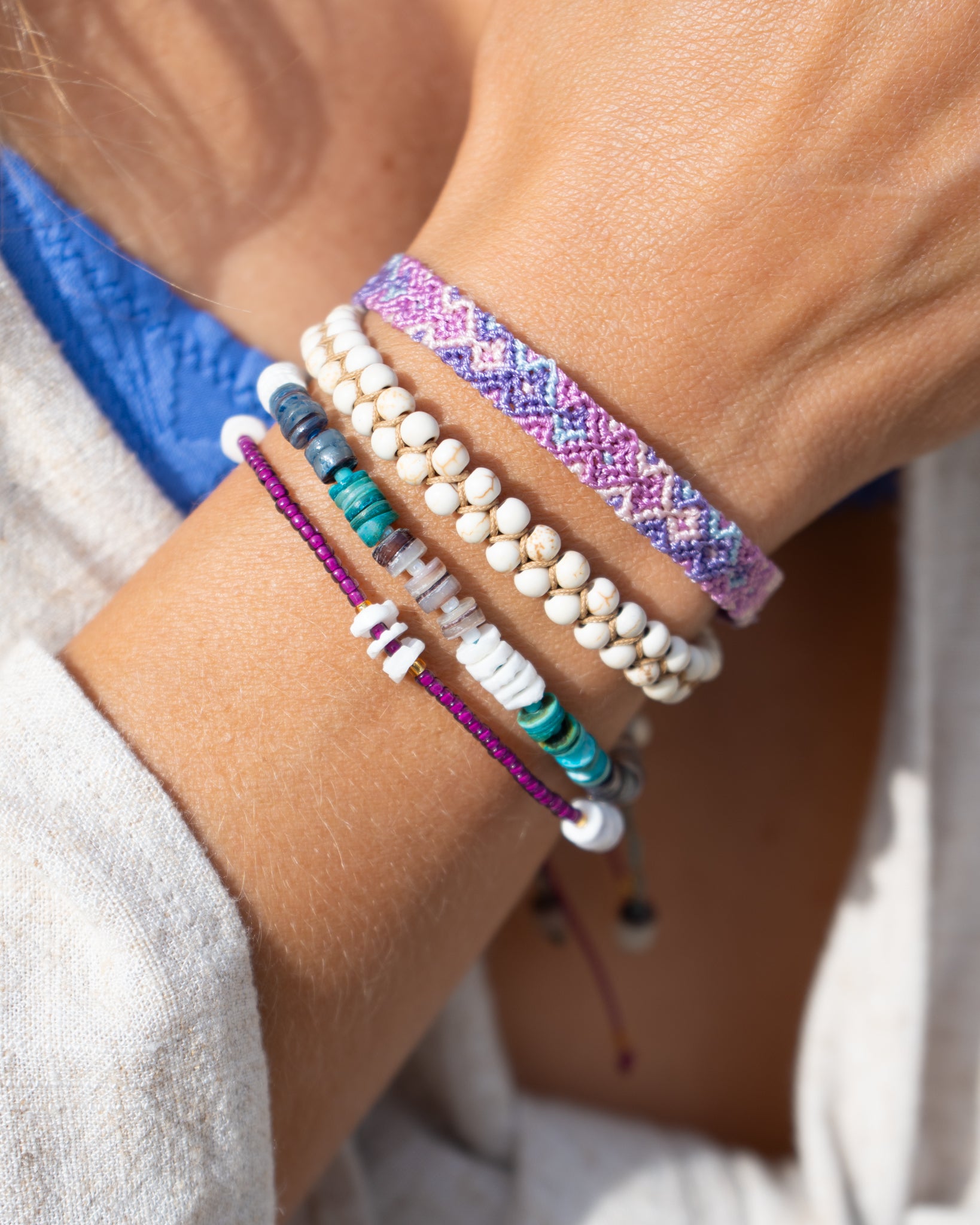 Purple woven bracelet worn in a stacked beach-inspired look.