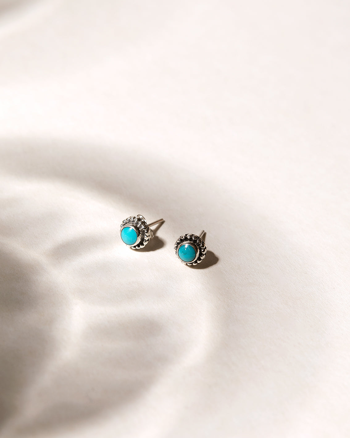 Silver stud earrings with turquoise stones photographed in soft natural light